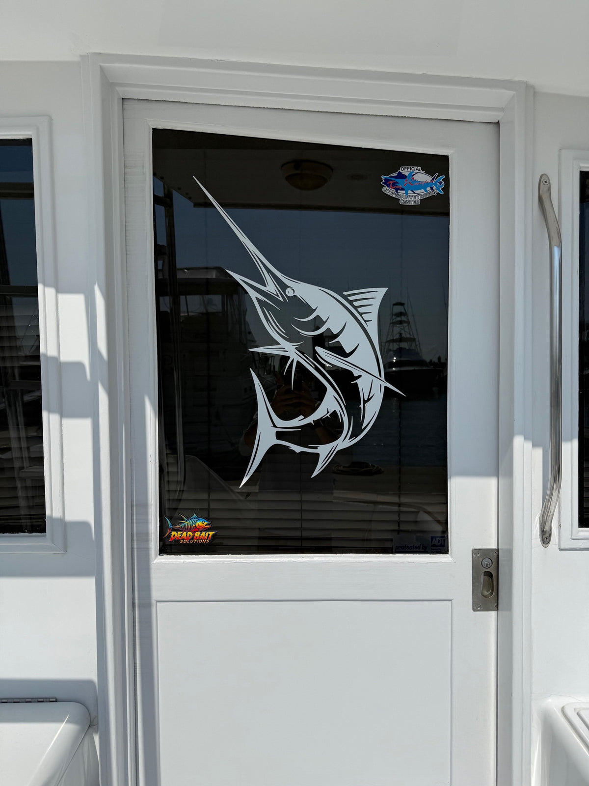 Glass door with a fish design and Meguiar's logo on a vehicle