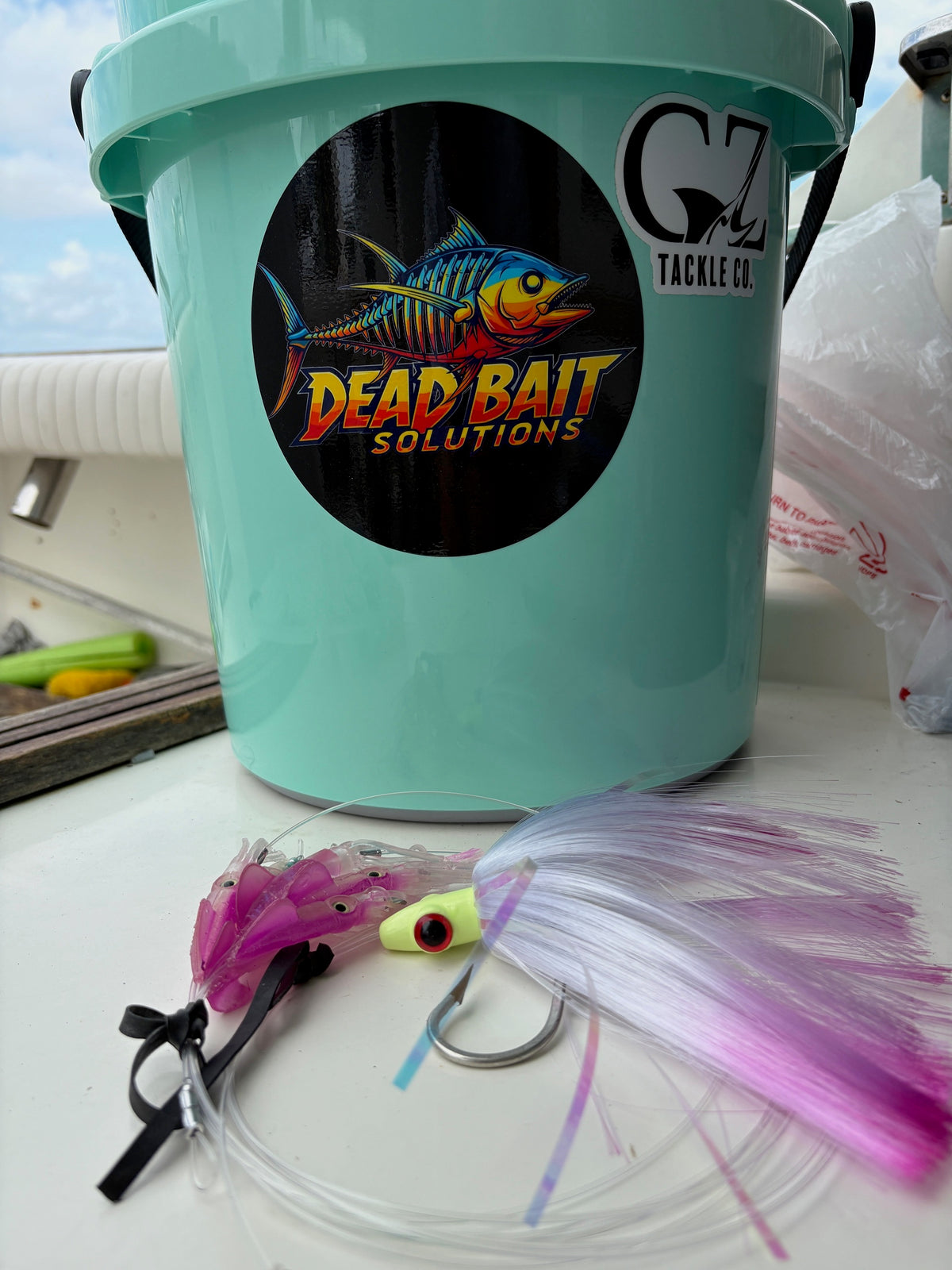 Teal tackle box with 'Dead Bait Solutions' logo and fishing lures on a white surface.